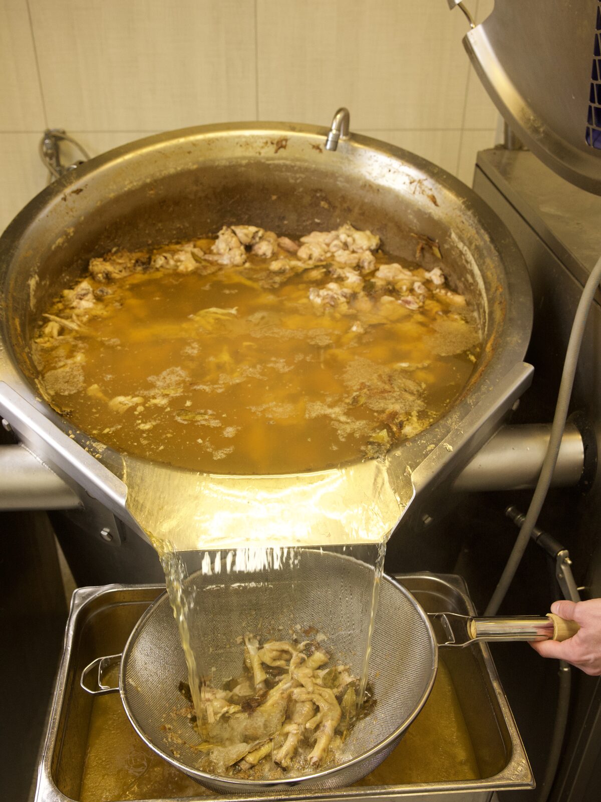 Kraft tappes fra en stor vippegryte gjennom en sil ned i et stålkar